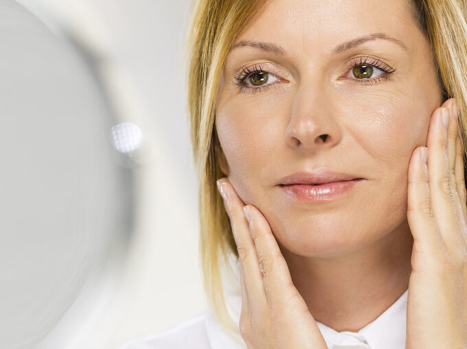 Woman looking in the mirror wondering if she's ready for a facelift in Plymouth, MN