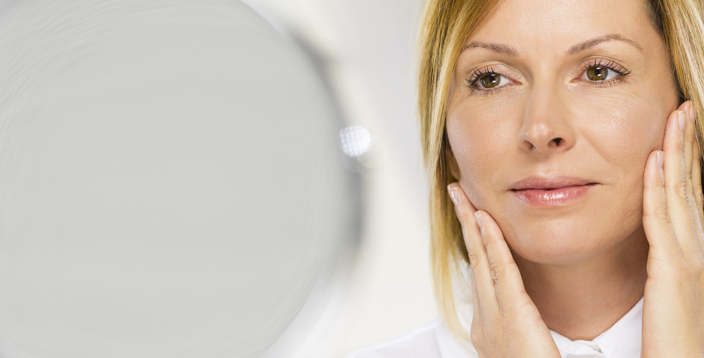 Woman looking in the mirror wondering if she's ready for a facelift in Plymouth, MN